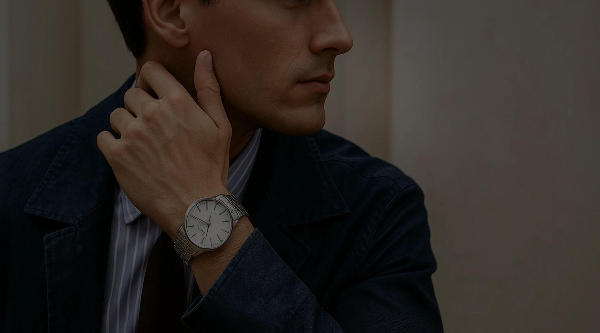 Man adjusting his collar with a watch on his wrist against a neutral background
