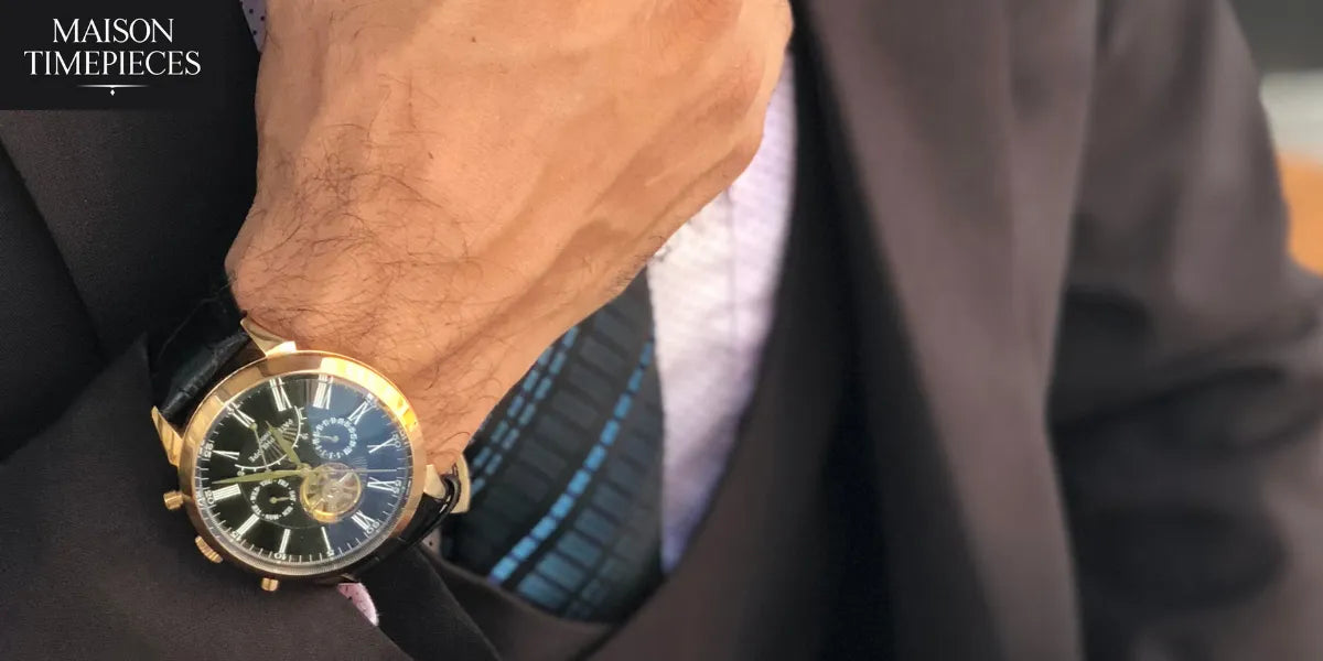 “Luxury gold men’s wristwatch with black leather strap worn with formal suit — Bovet-style elegance photographed by Maison Timepieces.”