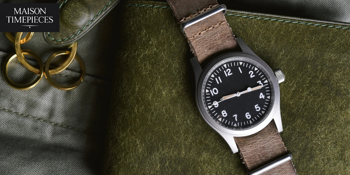 “Emporio Armani style field watch with black dial and brown leather strap on olive green background – Maison Timepieces Singapore”