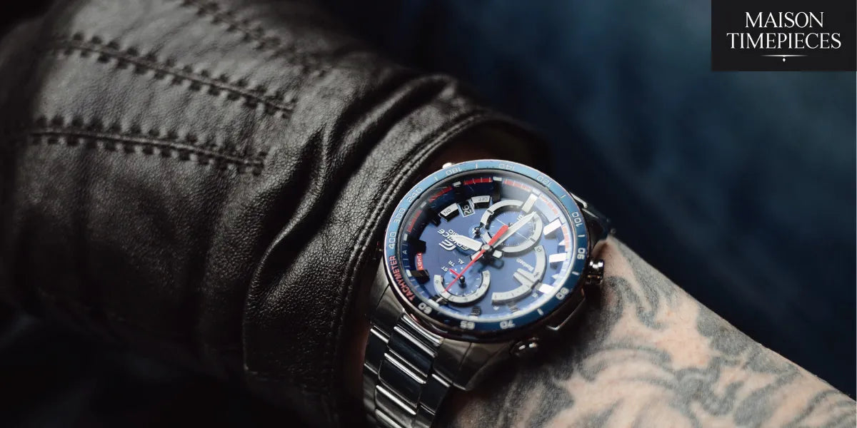 “Blue chronograph sports watch on stainless steel bracelet worn over leather gloves — photographed for Maison Timepieces.”