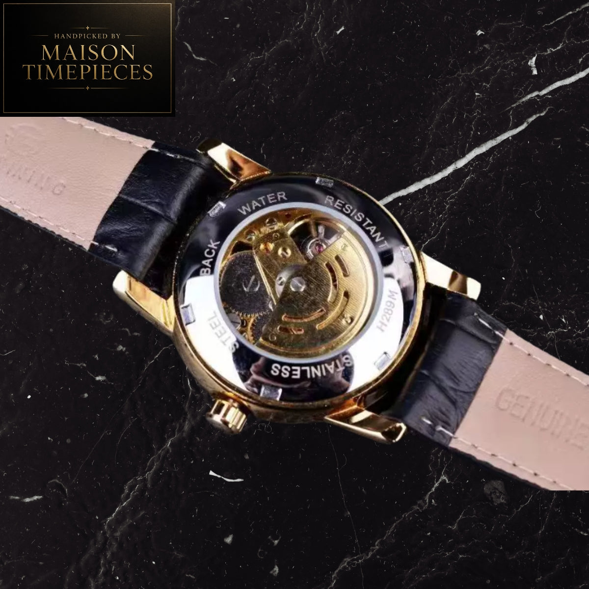 A close-up of a wristwatch shown from the back, featuring a gold-tone case with a transparent dial that reveals the mechanical movement, paired with a black and beige leather strap. The watch is displayed on a black marble surface, with a Maison Timepieces logo in the top-left corner.