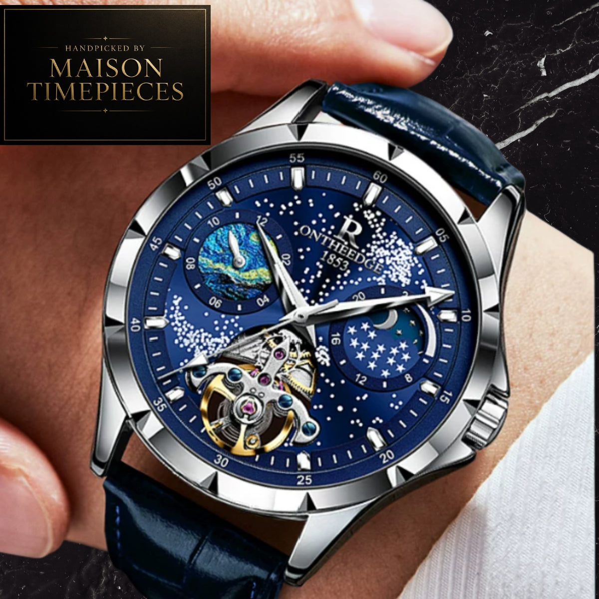 A close-up of a wristwatch being worn, with a hand holding the strap. The watch has a silver-tone case, a deep blue dial with moonphase and starry details, and a dark blue leather strap.