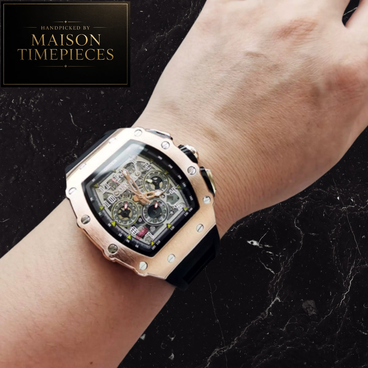 A luxury skeleton watch with a rose gold-toned case and black strap, worn on a person's wrist against a black marble background. A logo for 'MAISON TIMEPIECES' is visible in the top left corner.