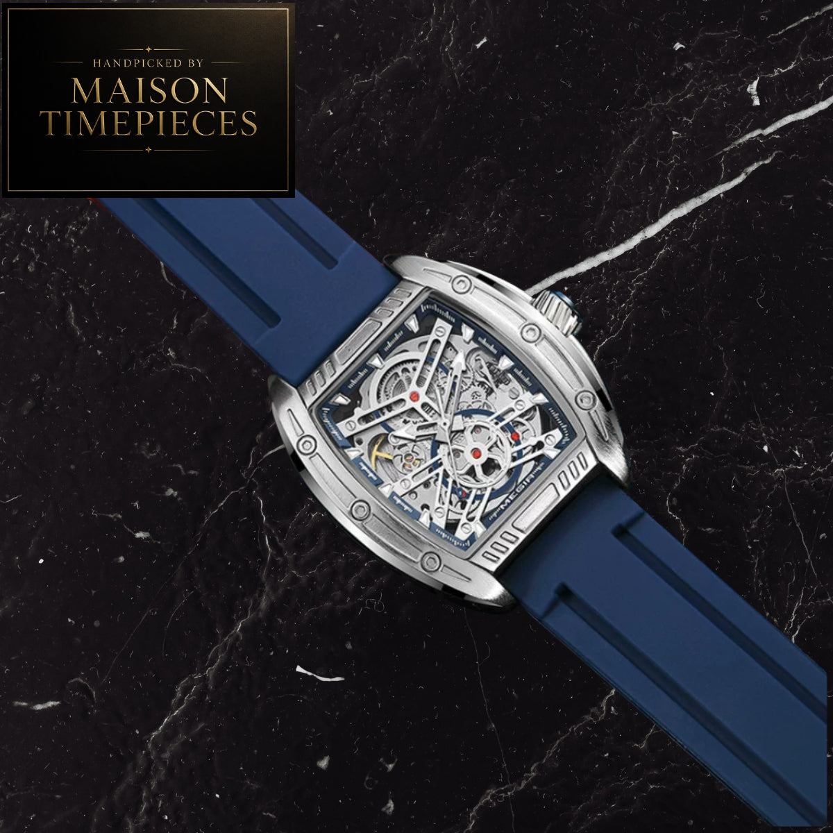 A skeleton watch with a blue rubber strap and a silver-toned case, displayed diagonally on a black marble background. A black logo badge in the top-left corner reads 'Handcrafted by Maison Timepieces'.