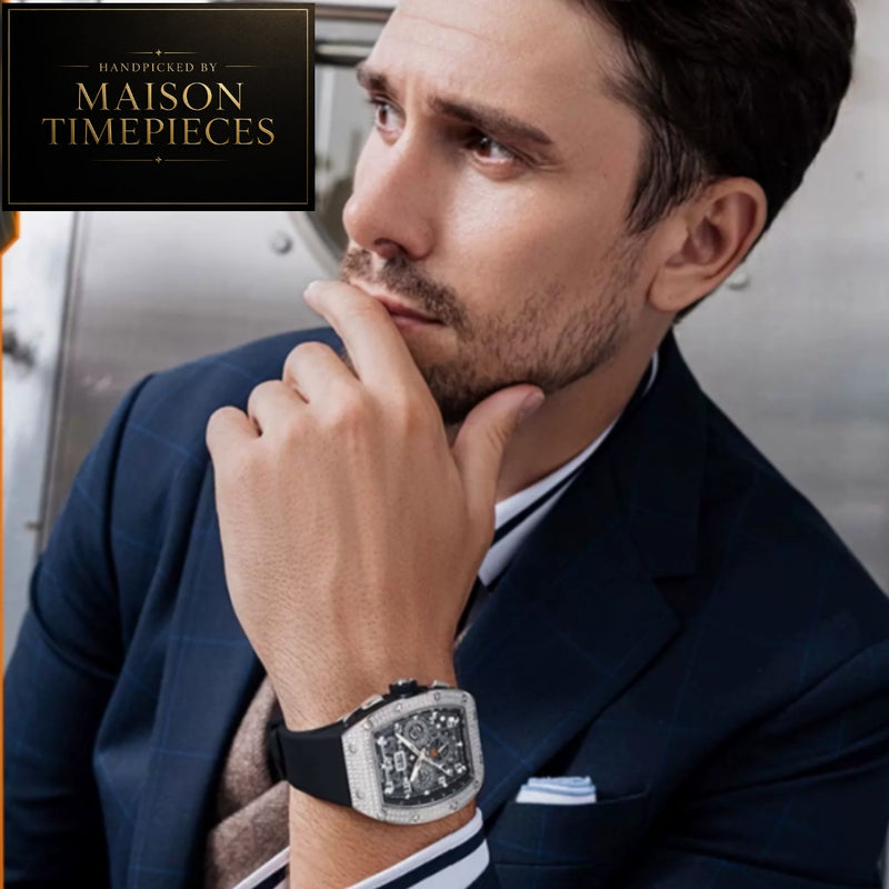 A man in a navy suit wearing a Maison Timepieces watch, with a logo overlay in the top-left corner.