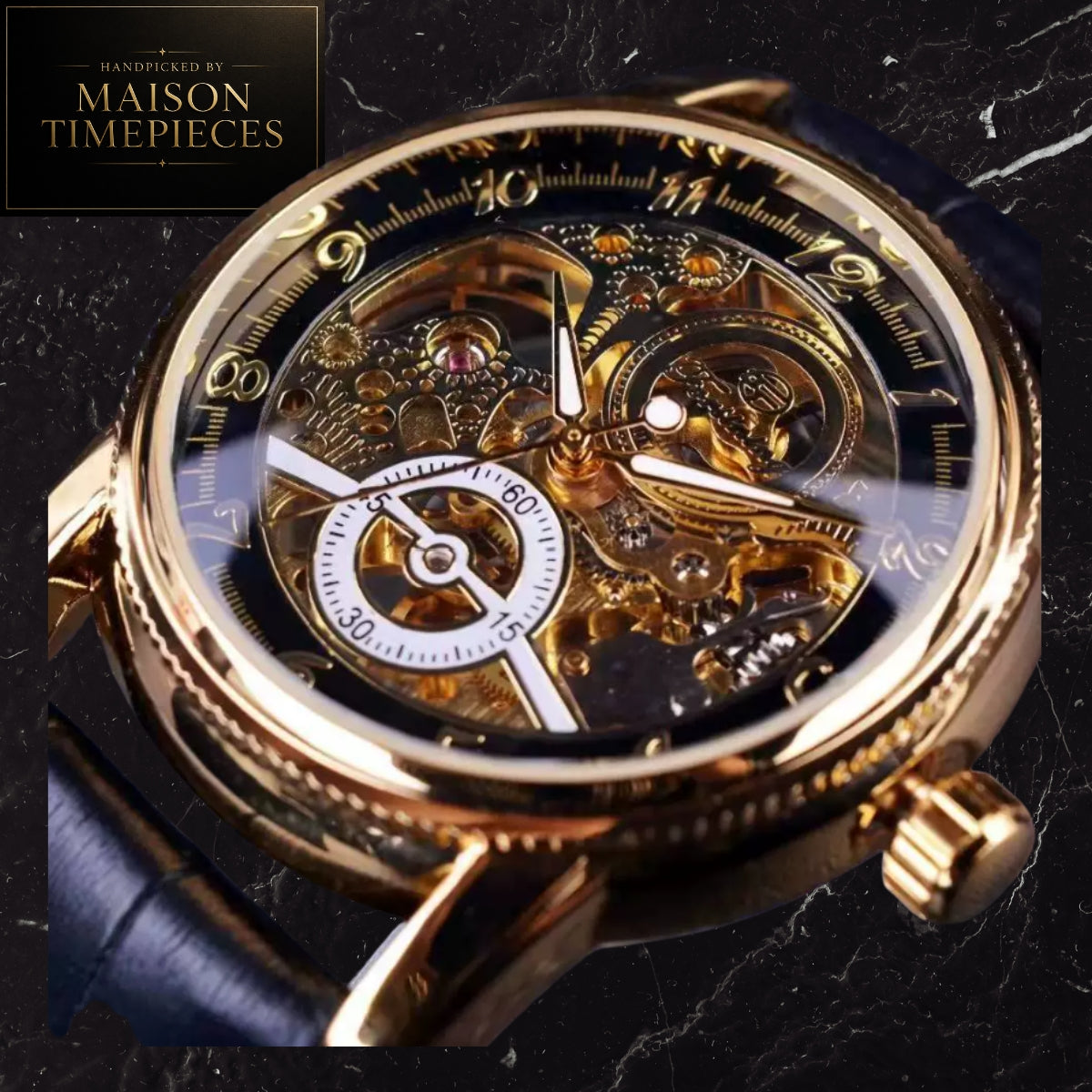 A close-up of a skeleton wristwatch with a gold-tone case, transparent dial showing intricate internal gears and mechanics, white subdial details, and a dark blue leather strap on a dark marble background. A black square logo in the top-left reads 'Handpicked by Maison Timepieces'.