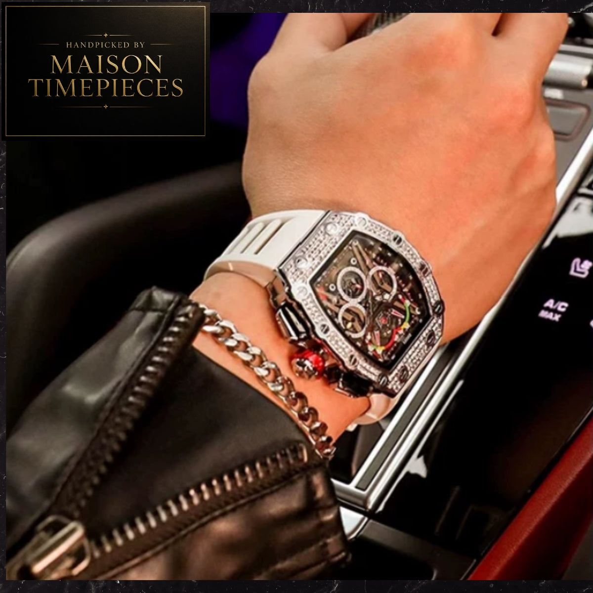 A close-up lifestyle shot of a wrist wearing a Maison Timepieces luxury watch. The watch features a silver-toned case encrusted with clear stones, a white rubber strap, and a skeleton dial showing the inner mechanical movement.