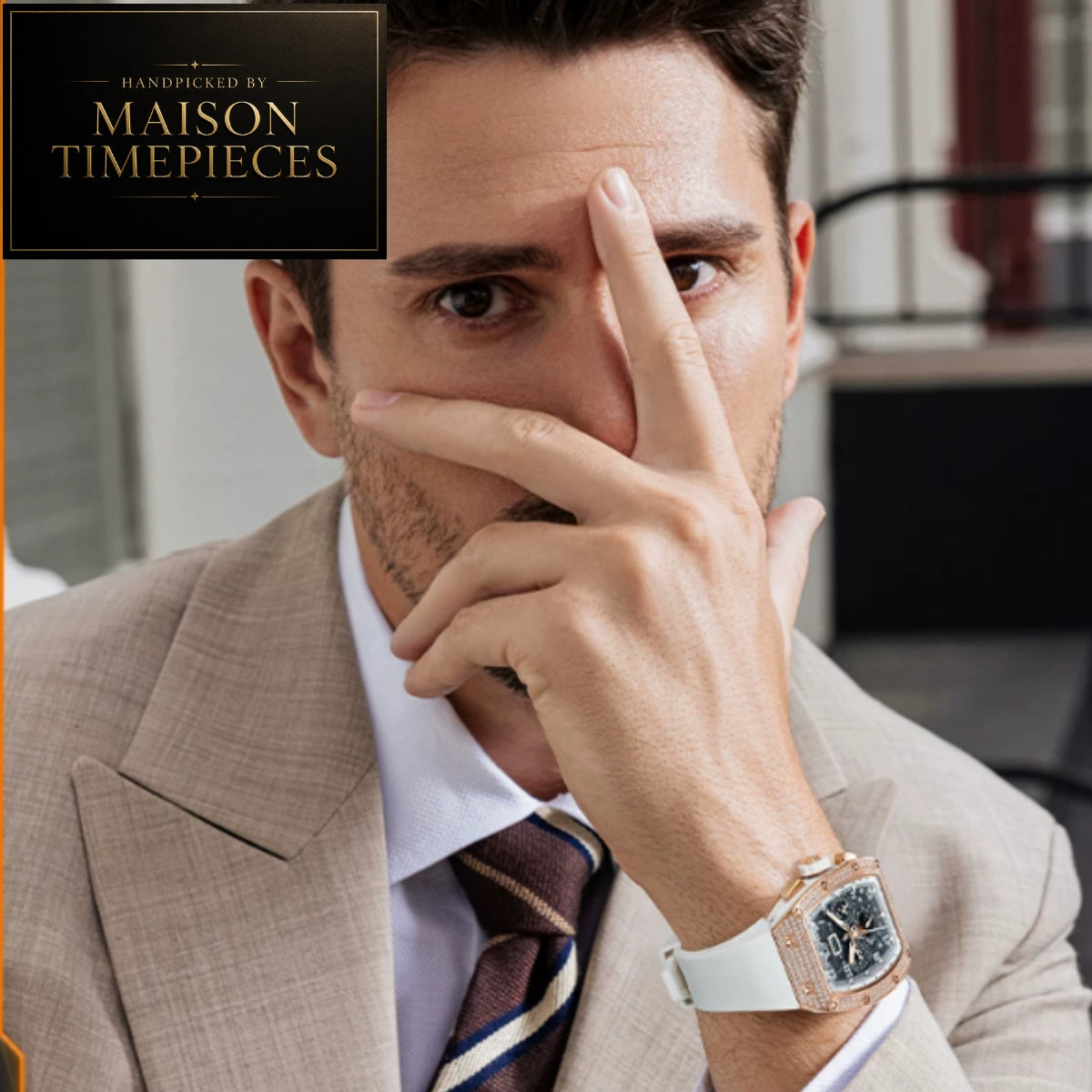 A man in a beige suit and striped tie wears a Maison Timepieces watch with a white strap and rose gold-toned case. A Maison Timepieces logo overlay is visible in the top left corner.
