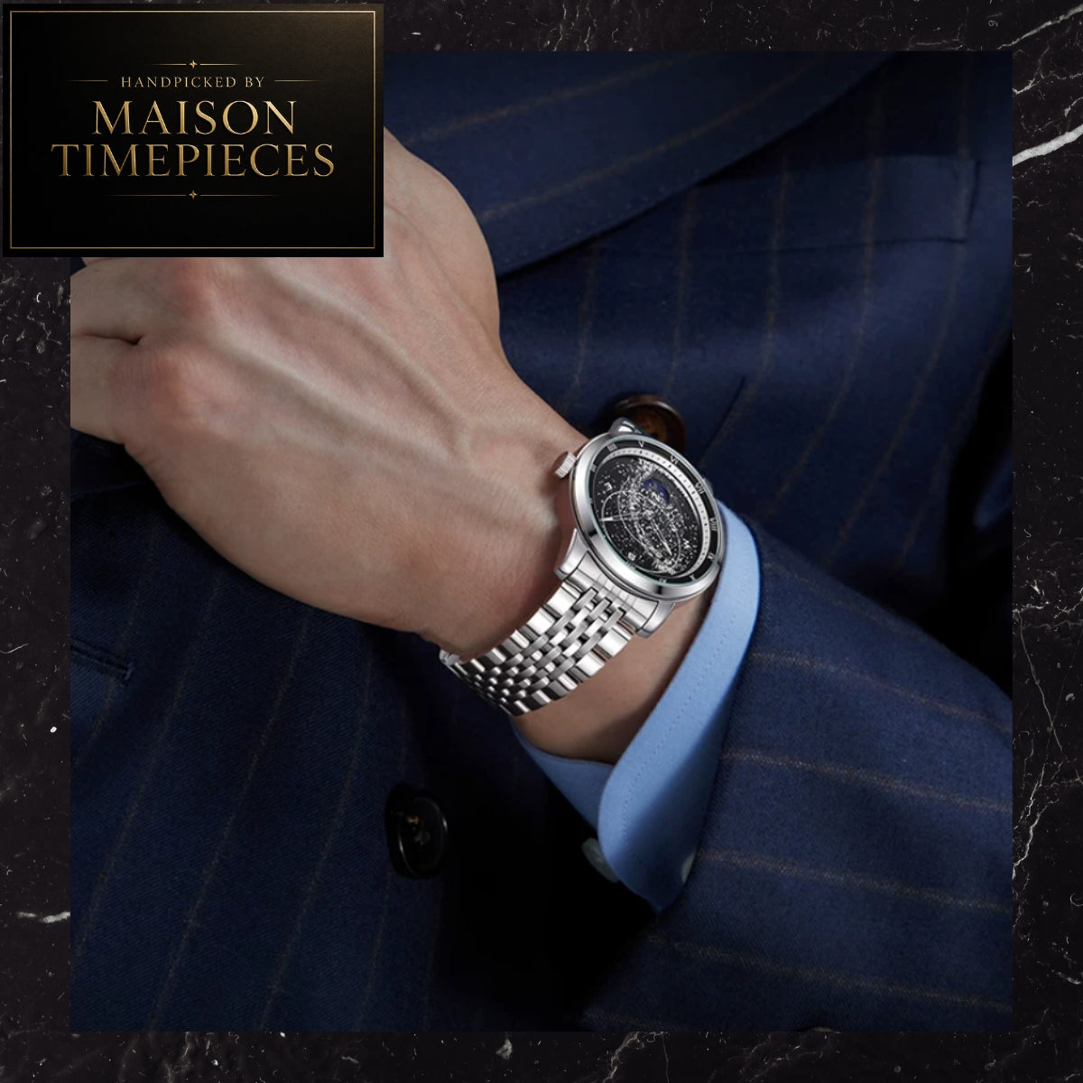 A silver-toned stainless steel watch with a multi-dial face and link bracelet worn on a man's wrist, styled with a blue pinstripe suit jacket and light blue dress shirt. A black brand badge in the top-left corner reads 'Handpicked by Maison Timepieces'.