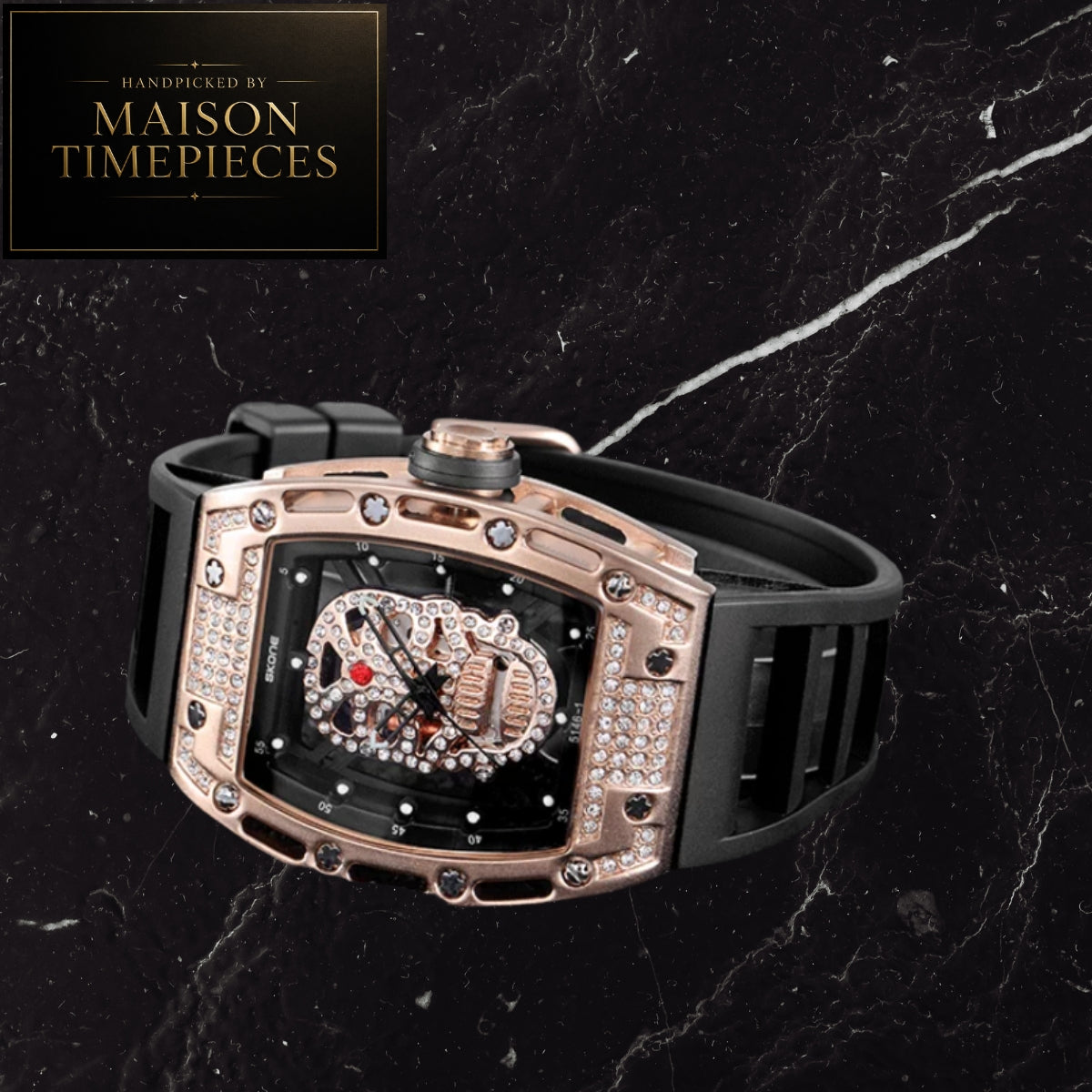 A luxury watch by Maison Timepieces featuring a rose gold-tone case encrusted with diamonds, a black dial with skeletonized details, and a black rubber strap, set against a dark marble background.