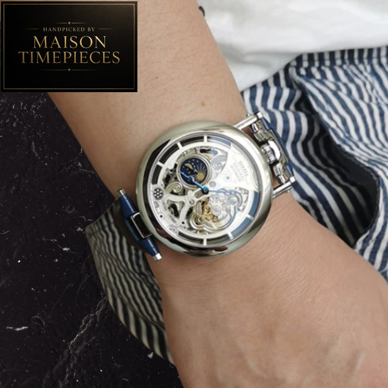 A close-up of a skeleton wristwatch with a silver-toned case and blue accents, worn on a person's wrist. The watch face is open, showing the inner mechanical movement.