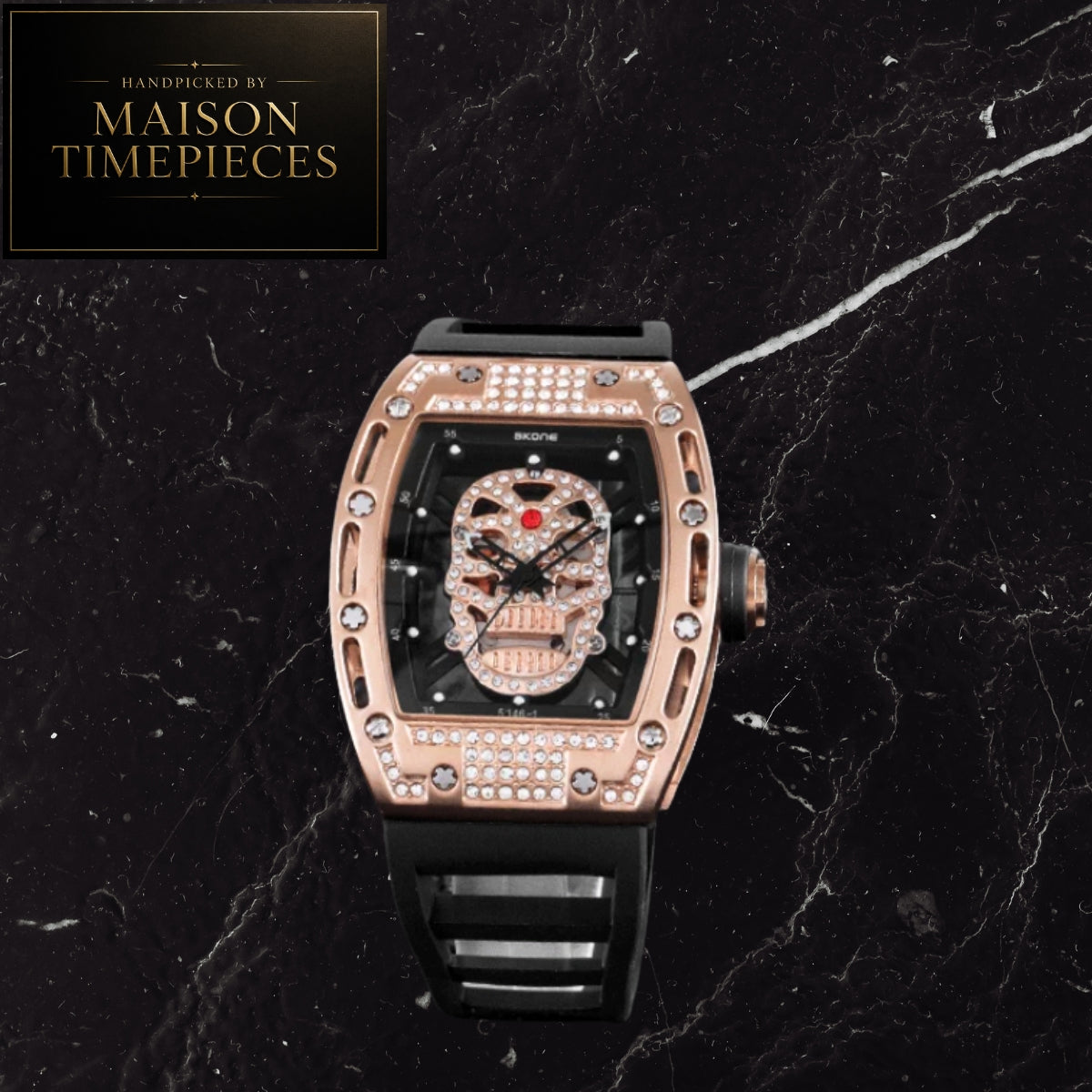A luxury skeleton watch by Maison Timepieces, featuring a rose gold case encrusted with clear crystals, a black dial with a skull skeleton design, and a black strap, set against a black marble background.