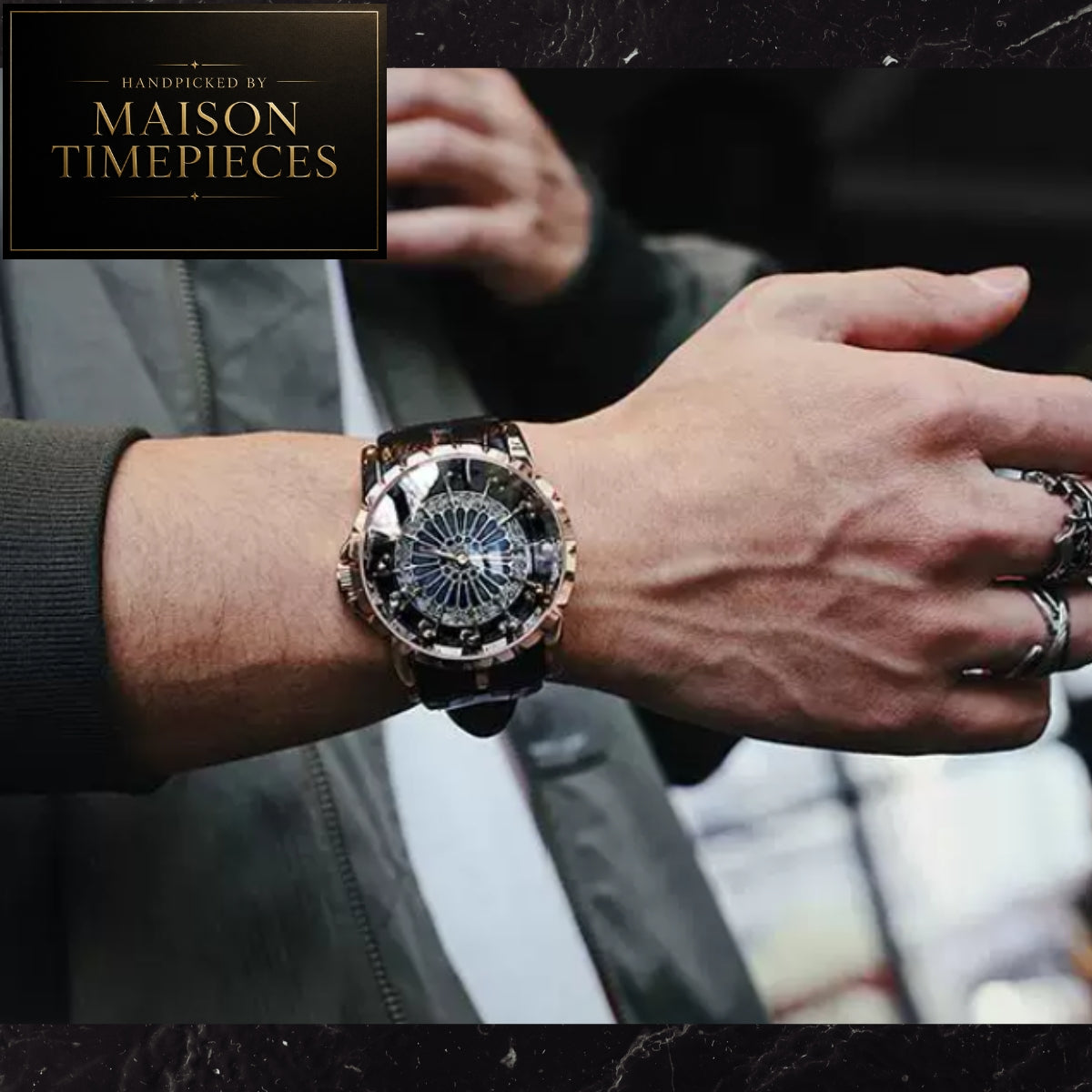 A men's wristwatch with a dark dial, rose gold-toned case, and dark strap, shown worn on a person's wrist. The image includes a black branded overlay in the top-left corner reading 'Handcrafted by Maison Timepieces'.