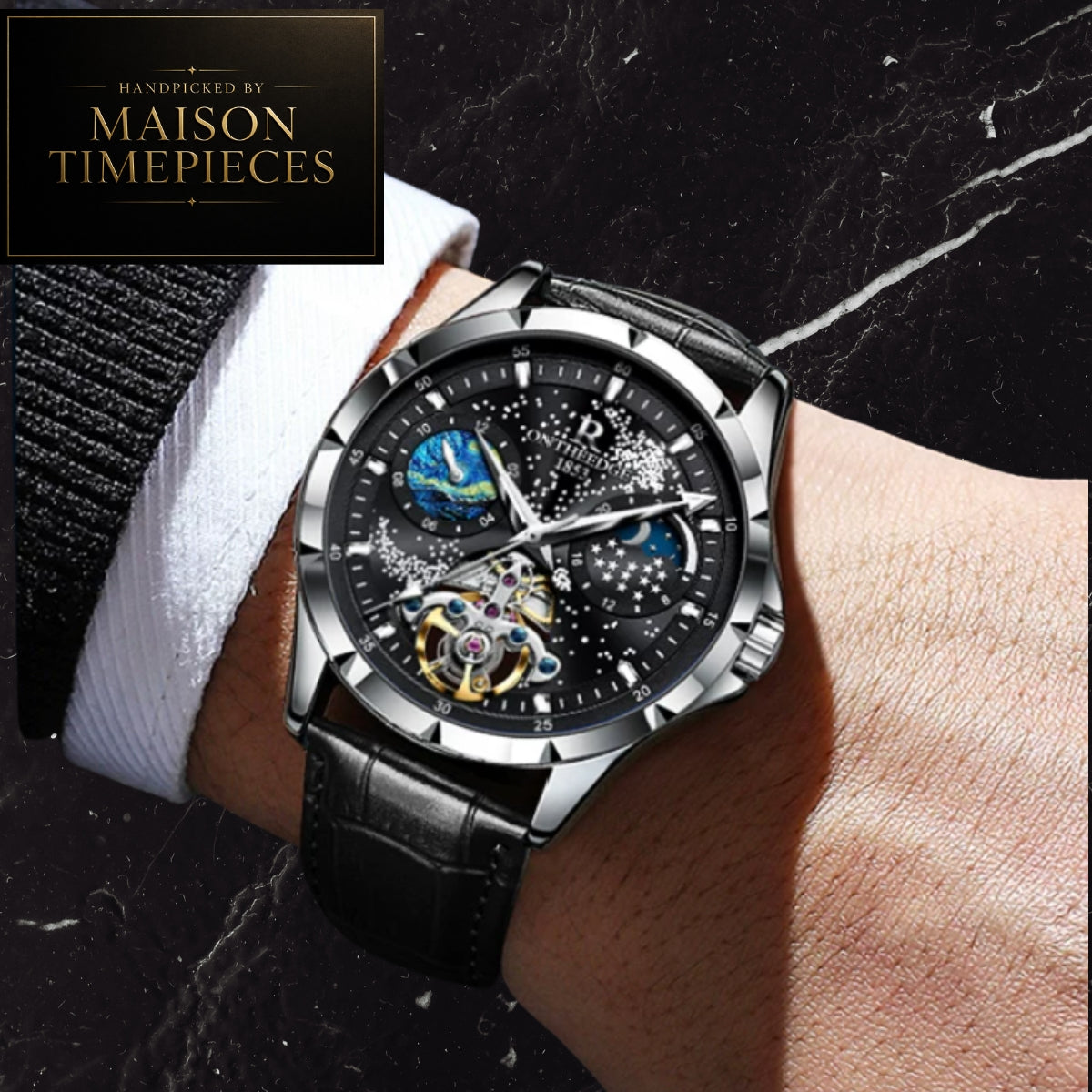 A wristwatch with a black dial, silver-toned case, and black leather strap worn on a person's wrist against a dark marble background. A black brand badge in the top-left corner reads 'DANDED BY MAISON TIMEPIECES'.