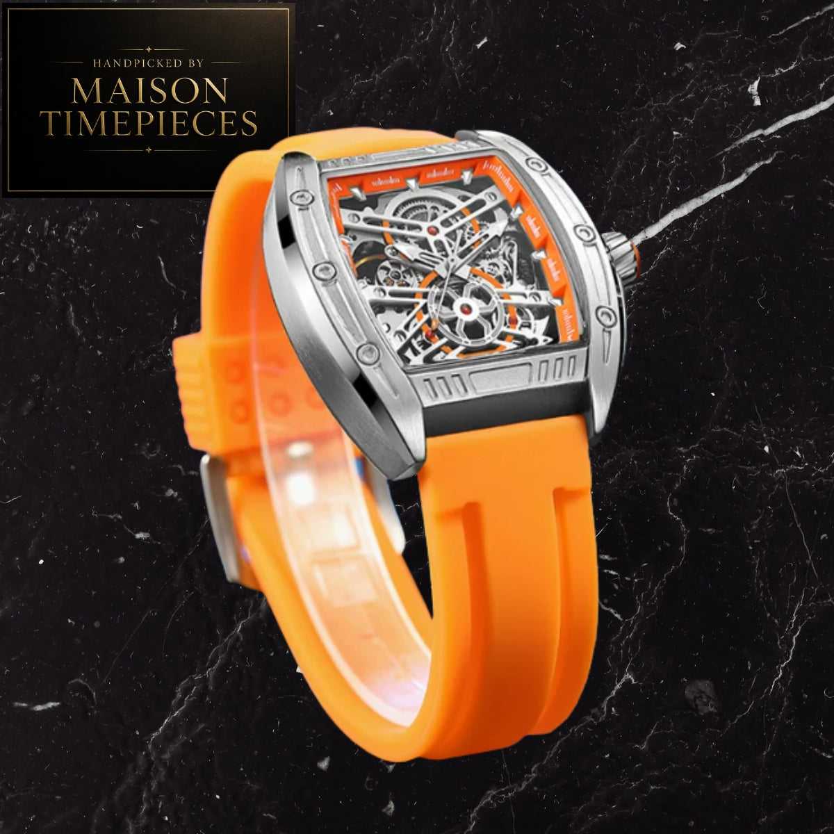 A skeleton watch with a bright orange silicone strap and a silver-toned case, displayed on a black marble background. A 'Handmade by Maison Timepieces' logo is visible in the top-left corner.