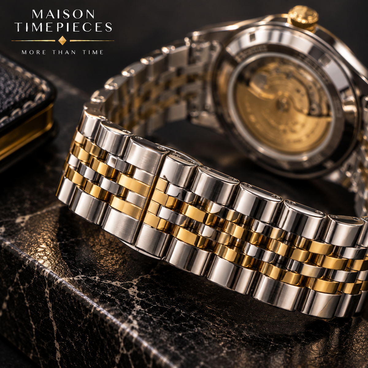 A close-up of a two-tone stainless steel watch bracelet with gold accents, shown on a dark marble surface with the watch case partially visible in the background. The Maison Timepieces logo appears in the top left corner.