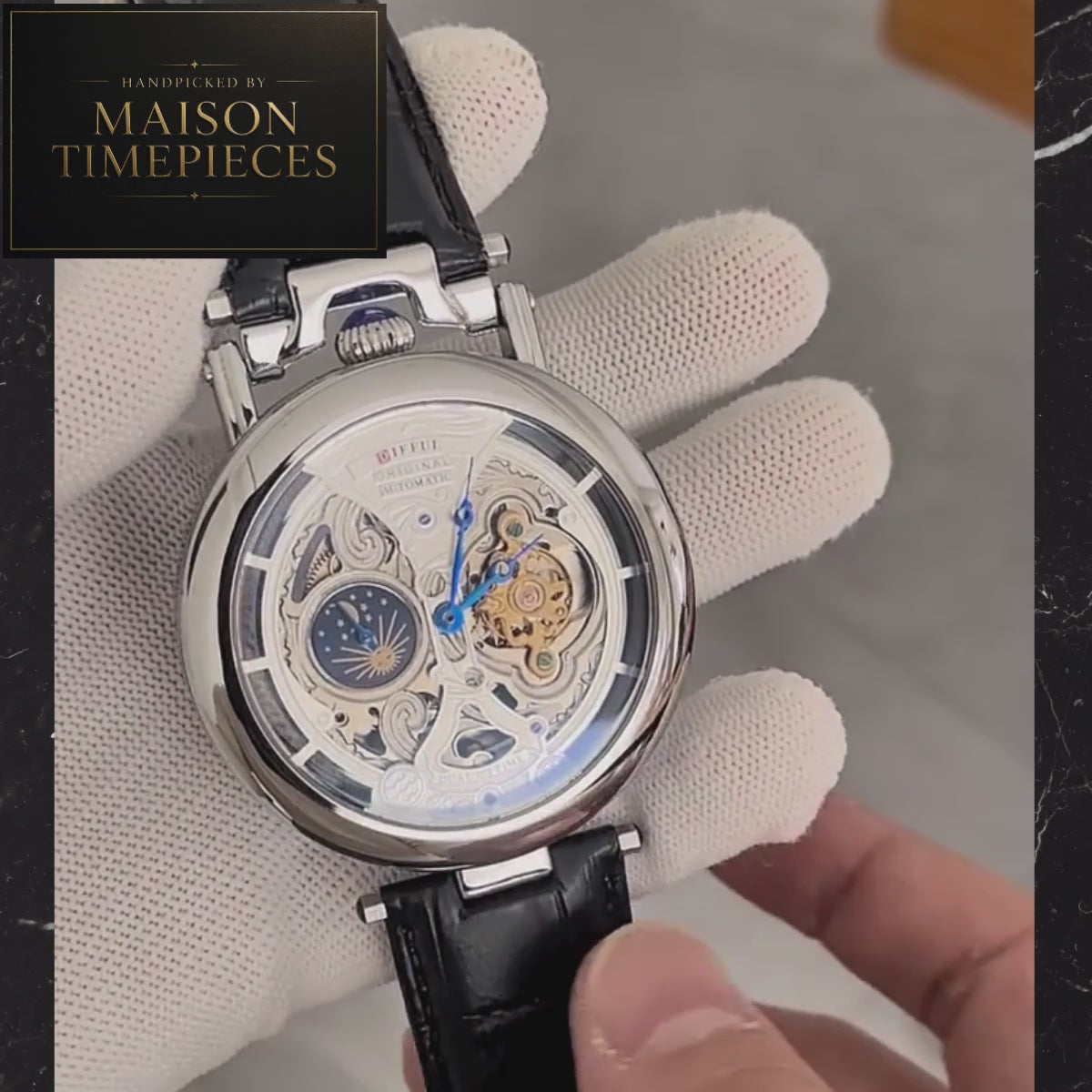 Maison Timepieces Curated automatic skeleton moonphase dress watch with blue leather strap, silver skeleton dial, exhibition mechanical movement and 49mm polished case.